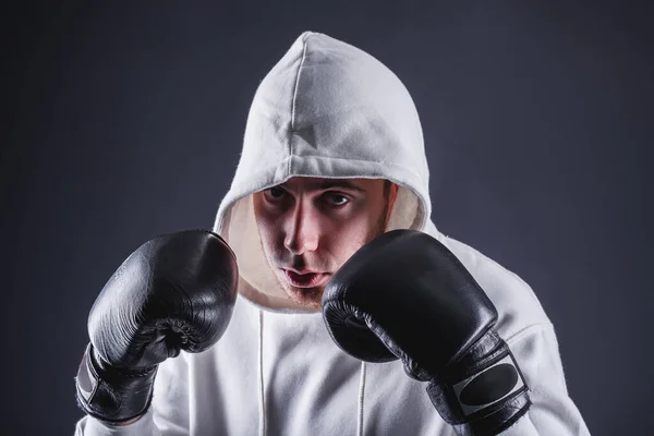 Jeune homme en gants de boxe et un sweat-shirt blanc sur fond sombre dans le studio. Le concept de victoires et de batailles — Photo