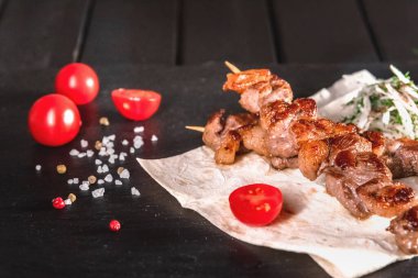 Karanlık bir tahtanın üzerindeki şişte iştah açıcı et parçaları. Yemek ve servis konsepti