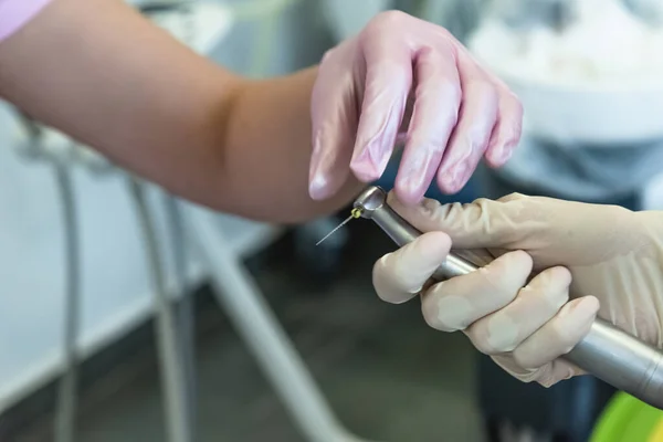 Primer plano de las manos de los médicos con un taladro dental en una clínica dental. Concepto de atención sanitaria y tratamiento — Foto de Stock