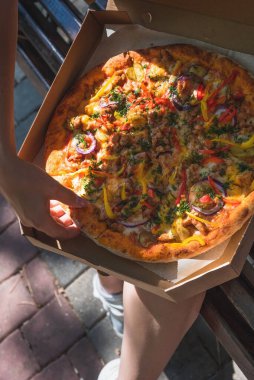 Caddedeki bir pizza kutusuna yakın çekim. Fast food, yemek teslimatı ve doğada öğle yemeği kavramı.