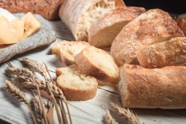 Beyaz bir tahta üzerinde dilimlenmiş köy ekmeği ve peyniri. Sağlıklı gıda ve tarım kavramı
