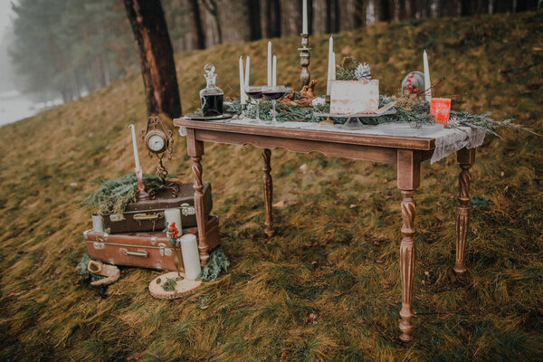 Still life with old vintage suitcases, clocks and candles on vintage table in autumn forest