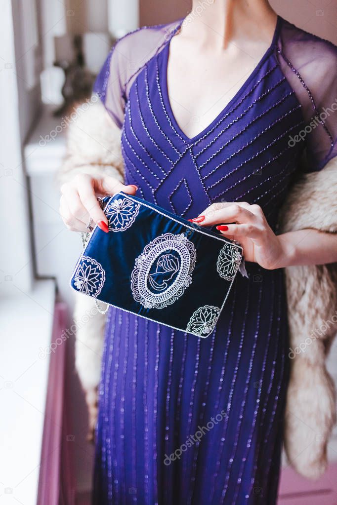 Elegant woman in violet dress holding vintage retro bag 