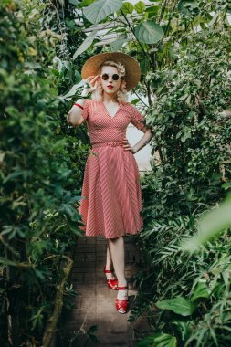 Tropik bahçede poz şapka şık kadın