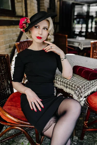 Retro görünümlü genç kadın küçük siyah elbise ve sevimli şapka