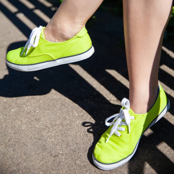 female legs in light green sneakers