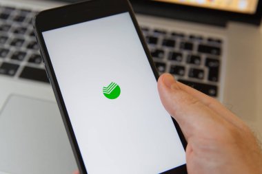 Moskova / Rusya - 20 Şubat 2019: bir iphone Macbook arka plan üzerinde tutarak. Sberbank logo üstünde perde