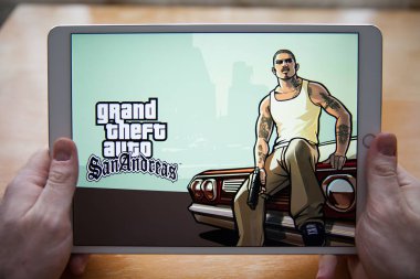 Moscow / Russia - February 25, 2019: White ipad in hand. On the screen, the game Grand Theft Auto clipart