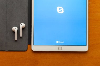Moskova / Rusya Federasyonu - 15 Mart 2019: masaya ekranın üzerinde beyaz ipad yalan olduğunu Skype programı. Yakınlardaki kablosuz kulaklıklar vardır