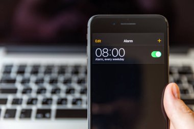 Moskova / Rusya Federasyonu - 15 Mart 2019: el Macbook arka plan üzerinde siyah iphone. Çalar saat 8: 00 ile ayarlanır