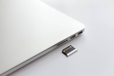 Beyaz masada kapalı metal dizüstü bilgisayar. Adaptör kart okuyucusuna yakın