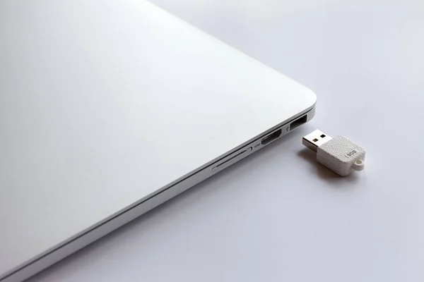 Beyaz masada kapalı metal dizüstü bilgisayar. Beyaz USB flash sürücünün yanında 8 GB