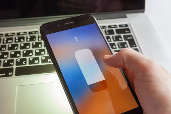 Moskova/Rusya-5 Nisan 2019: bir siyah iPhone bir MacBook arka planına karşı elinde bir el feneri tutan