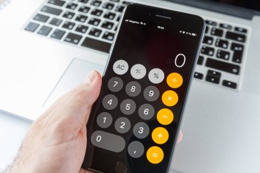 Moskova/Rusya-10 Nisan 2019: MacBook arka planda elle siyah iPhone. Ekran içi uygulama hesap makinesi