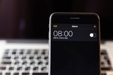 Moskova/Rusya-13 Nisan 2019: siyah iPhone 8 Plus MacBook arka planda. Alarm saati 8 ' de kapalıdır.