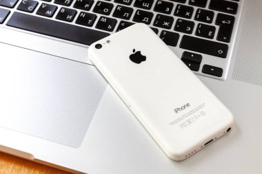 Moskova / Rusya - 11 Mayıs 2019: Macbook klavyede beyaz ters iphone 5c yatıyor.