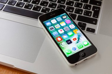 Moskova / Rusya - 11 Mayıs 2019: Beyaz iphone 5c klavye macbook yatıyor. Uygulama ekranında
