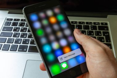 Moskova / Rusya - 14 Mayıs 2019: Macbook arka planda elinde siyah iphone. iphone ekranında yeni mesaj