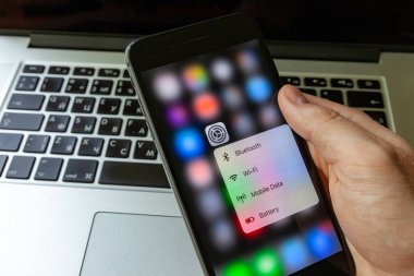 Moskova / Rusya - 14 Mayıs 2019: Macbook arka planda elinde siyah iphone. 3d dokunmatik kurulum menüsünün iphone ekranında
