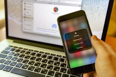 Moskova / Rusya - 17 Mayıs 2019: Elinde siyah iphone, airdrop ekranda. Macbook'un arka planında