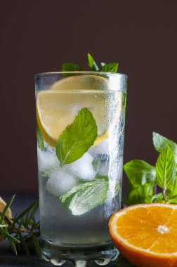 Mojito kireç ve highball cam bir koyu gri taş zemin üzerine nane kokteyli. Buz, beyaz rom, limon suyu ve tonik, bir sürü taze içkiyle dekore nane yaprakları, portakal ve limon dilim kopya alanı.