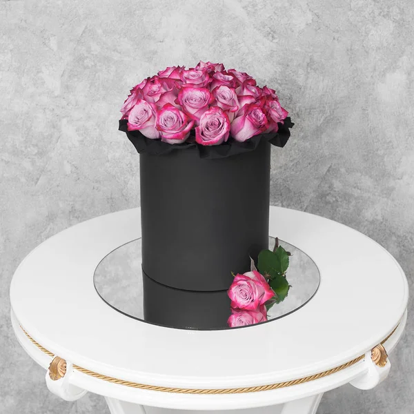 Kytice květin v krabici s kloboukem na stole — Stock fotografie