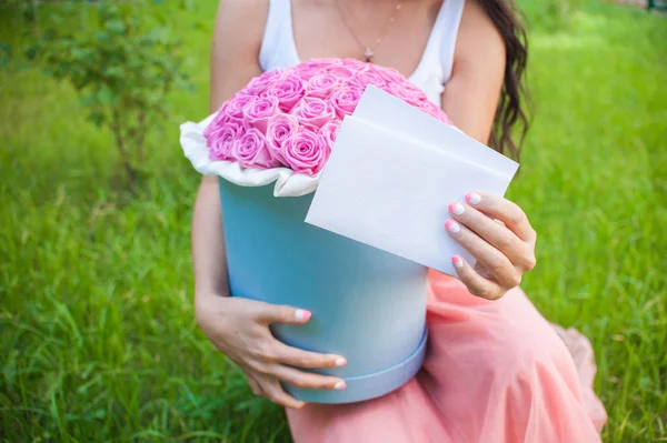 A bouquet of flowers in a hat box in the girl's hands — Stock Photo, Image