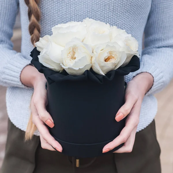 a bouquet of flowers in a hat box in the girl's hands