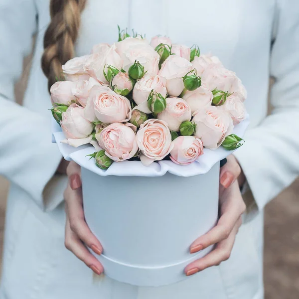 a bouquet of flowers in a hat box in the girl\'s hands