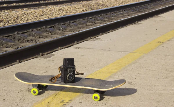 Câmera vintage em um skate no fundo do asfalto — Fotografia de Stock