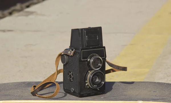 Vintage camera on a skateboard on the background of asphalt — Stock Photo, Image