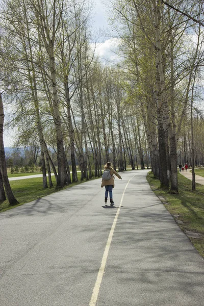 Mädchen fährt auf Rollschuhen auf dem Asphaltweg im Stadtpark — Stockfoto