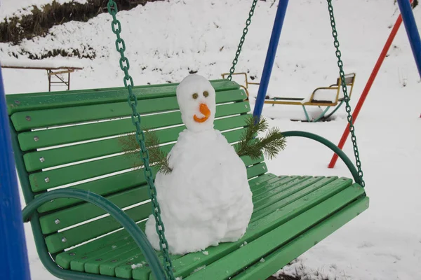 Plötzlich gab es starken Schneefall. Sie bastelten einen Schneemann und stellten ihn auf eine Bank. — Stockfoto