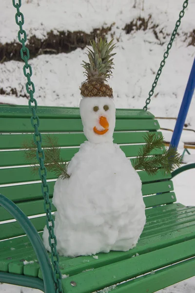 Plötzlich gab es starken Schneefall. Sie bastelten einen Schneemann und stellten ihn auf eine Bank. — Stockfoto