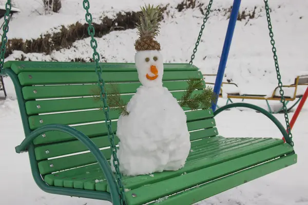 Plötzlich gab es starken Schneefall. Sie bastelten einen Schneemann und stellten ihn auf eine Bank. — Stockfoto