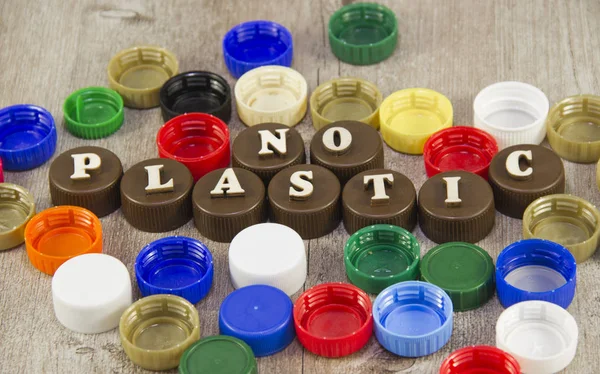 No plastic. Inscriptions in wooden letters on plastic bottle caps.