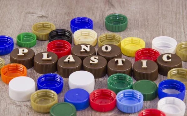 No plastic. Inscriptions in wooden letters on plastic bottle caps.