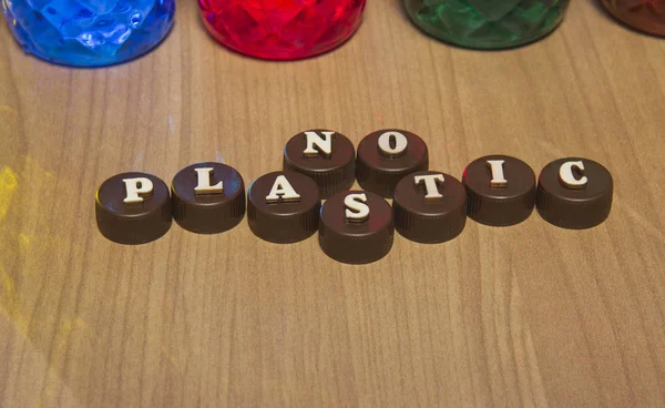 No plastic. Inscriptions in wooden letters on plastic bottle caps.