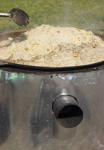 Cozinhar delicioso pilaf em um caldeirão ao ar livre — Fotografia de Stock