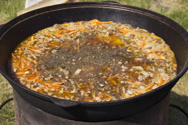 Cozinhar delicioso pilaf em um caldeirão ao ar livre — Fotografia de Stock