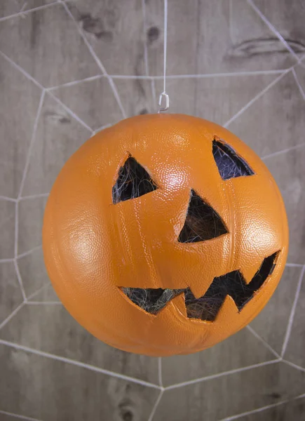 Jack lantern for Halloween of a basketball on a wooden background with spider webs.