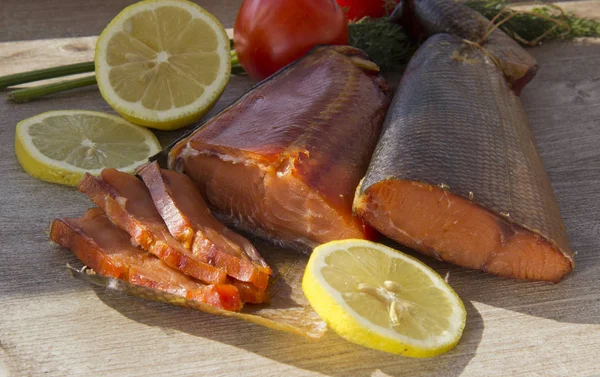 Peixe fumado, limão e um copo de cerveja em um fundo de madeira . — Fotografia de Stock