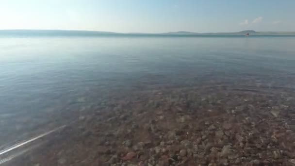 Водна поверхня озера в літній день, водяні човни плавають — стокове відео