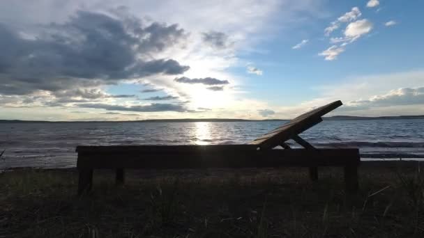 Die Sonne geht über den Horizont, die Wolken sind schnell am Himmel. Sonnenuntergang im Zeitraffer am See. — Stockvideo
