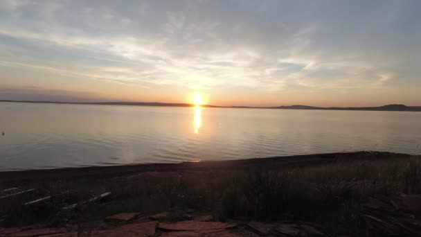 A nap megy át a horizonton, a felhők gyorsan az égen. Naplemente a timtiden a tó. — Stock videók