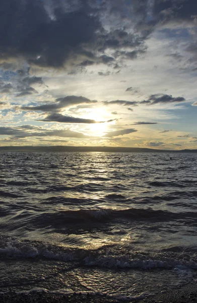 Sonnenuntergang, dramatische Wolken, Spiegelung der Sonne im Wasser des Sees — Stockfoto