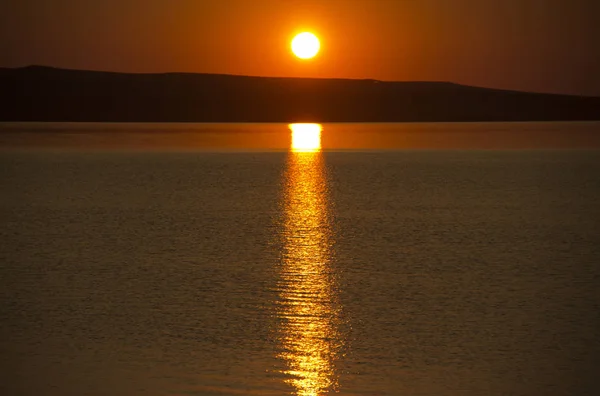 Belo pôr-do-sol laranja dourado sobre o lago. O sol se põe girando o céu tons amarelos, laranja e vermelho e reflete no lago . — Fotografia de Stock