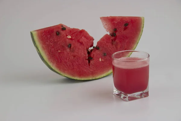 Skiva vattenmelon och ett glas saft på en vit bakgrund — Stockfoto