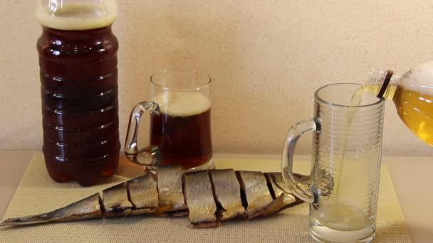 Bier wordt in een beker gegoten, op de tafel gesneden vis — Stockvideo