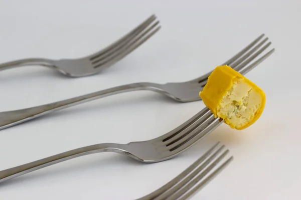 piece of curd cheese on a fork on a white background